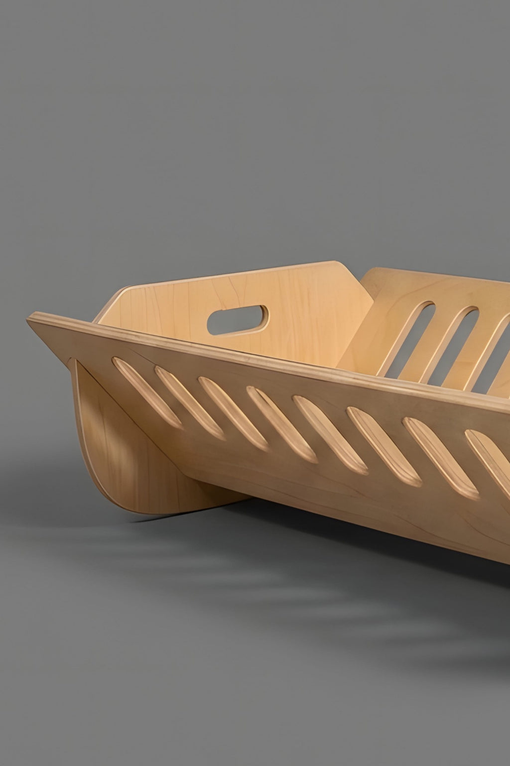 Wooden cot bed with cut-out design on a gray background